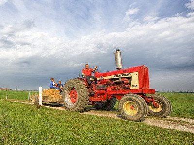  Tractor trailing wagon with passengers sitting on hay 